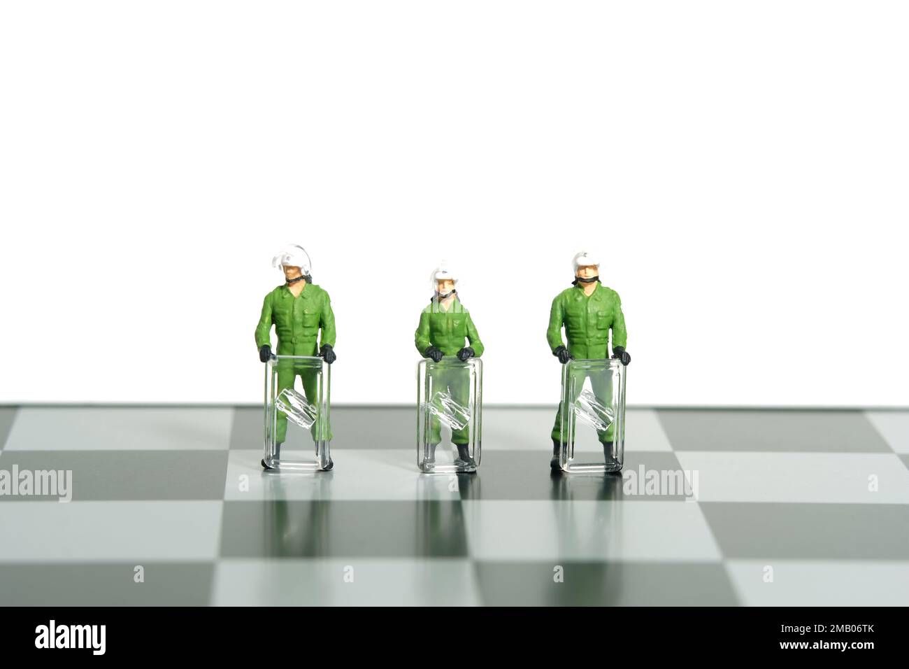 Miniature people toy figure photography. Protection strategy concept. A military anti riot armored army standing above chessboard. Isolated on white b Stock Photo