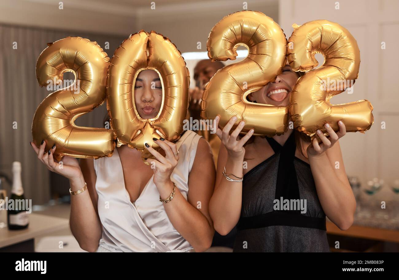Starting the year off with the right energy. a diverse group of friends standing together and holding up 2022 balloons during a New Years party. Stock Photo