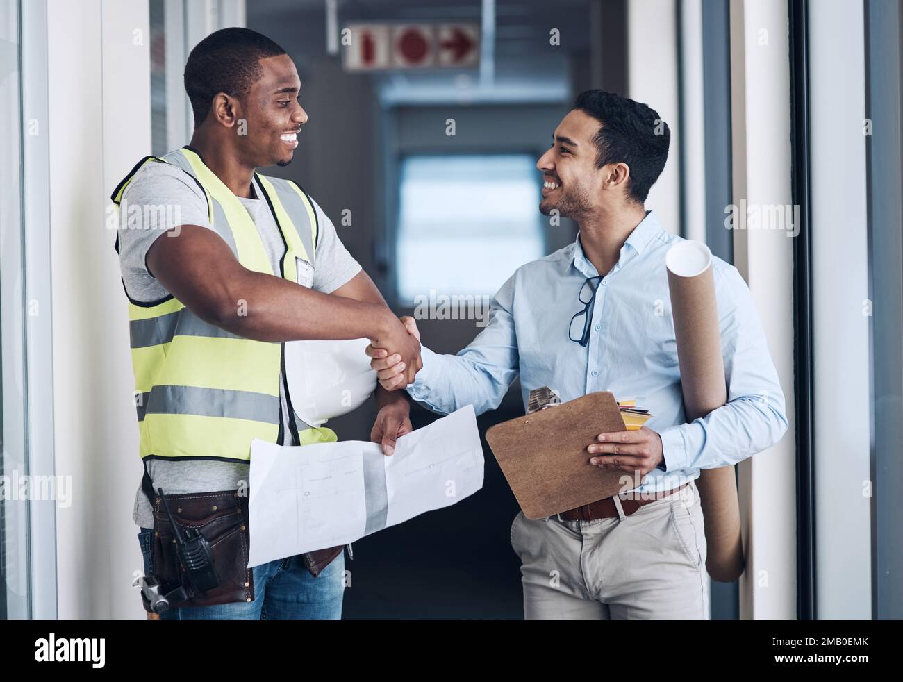 I cant wait to see your work. two young architects standing together and shaking hands after a discussion about the room before they renovate. Stock Photo