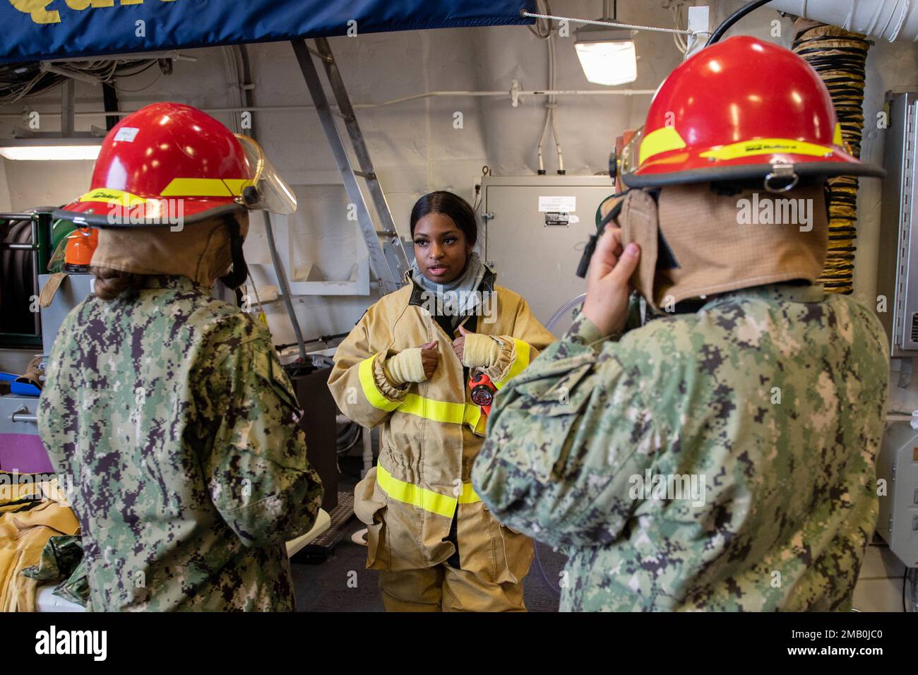 Damage Controlman 3rd Class Kyla Embry, assigned to the Zumwalt-class destroyer USS Michael Monsoor (DDG 1001), teaches U.S. Naval Sea Cadets how to properly wear a firefighter’s helmet aboard the ship during Portland Fleet Week 2022, June 9. Portland Fleet Week is a time-honored celebration of the sea services and provides an opportunity for the citizens of Oregon to meet Sailors, Marines and Coast Guardsmen, as well as witness firsthand the latest capabilities of today's maritime services Stock Photo