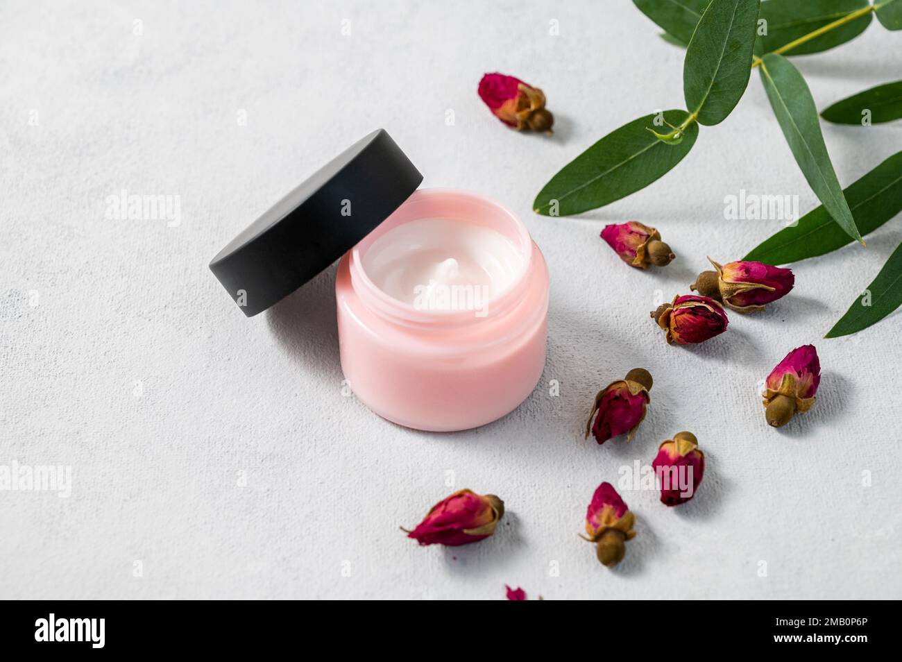 Face or body cream with rose  on a light background. The concept of care cosmetics with herb eucalyptus. Health and beauty. Copy space. Stock Photo