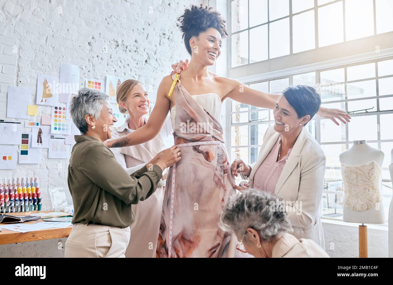 Model, designer women and dress fitting with help, design or teamwork for runway vision in workshop. Happy creative team, woman collaboration and Stock Photo