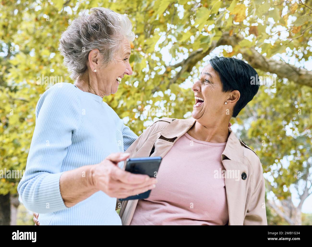 Senior women, laughing or phone meme in nature park, garden or relax environment in retirement, support or trust. Smile, happy friends or elderly Stock Photo