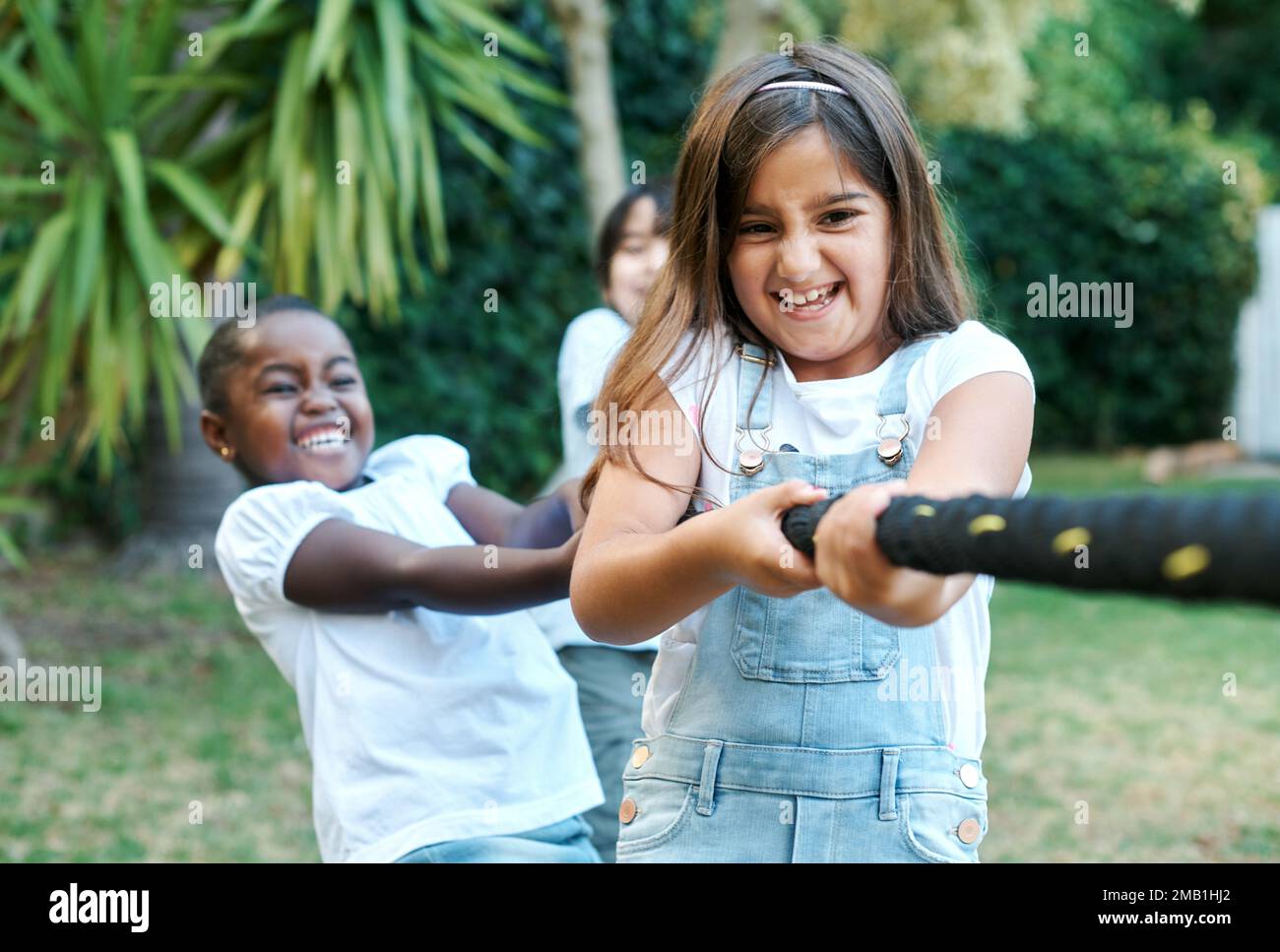 Im on the winning team. children playing tug of war together outside. Stock Photo