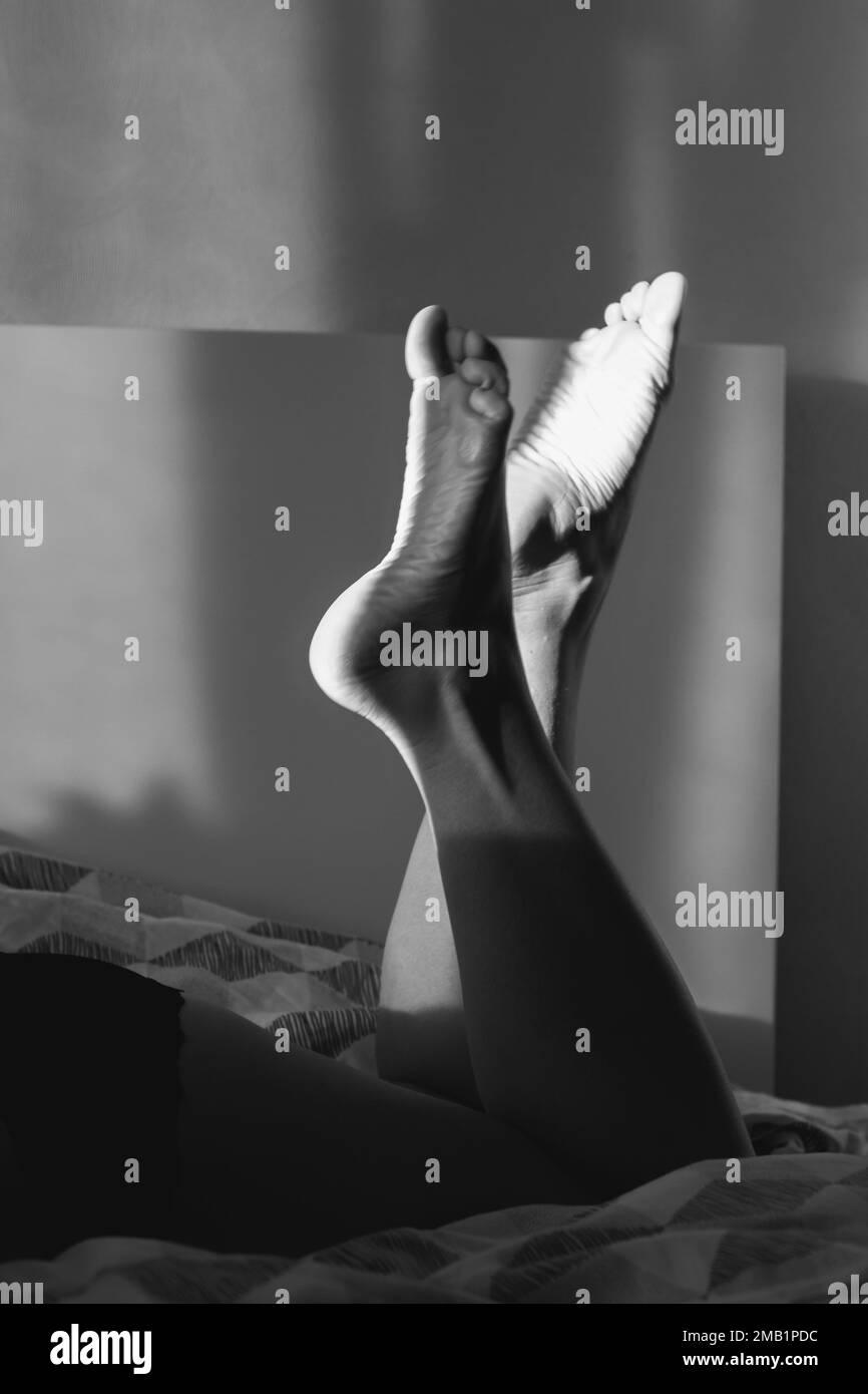 Close up barefoot legs lying on bed monochrome concept photo Stock Photo