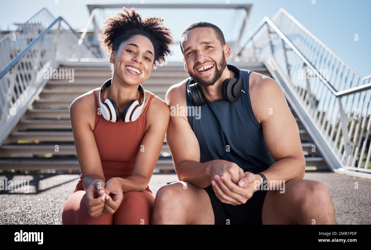 Sports, love and couple on stairs in city on break from exercise workout with smile and headphones. Motivation, health and fitness goals, man and Stock Photo