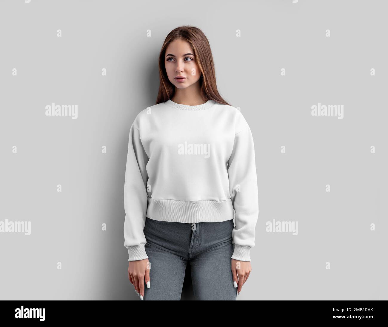 Mockup of a white female sweatshirt, a shirt on a girl in gray jeans, isolated on a background, front. Template of fashion empty crop clothes, longsle Stock Photo