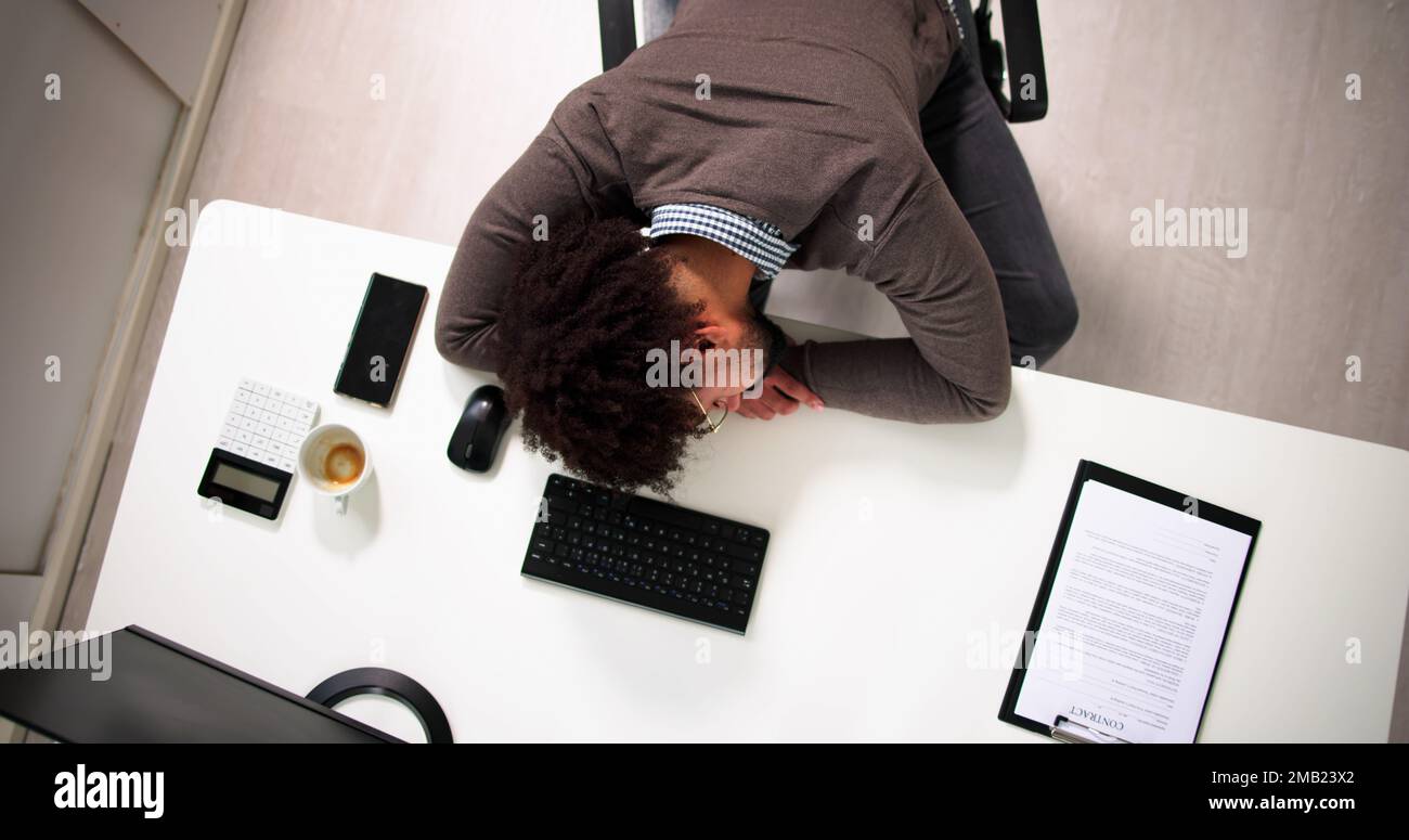 Tired African Businessman Sleeping In Office At Desk Stock Photo