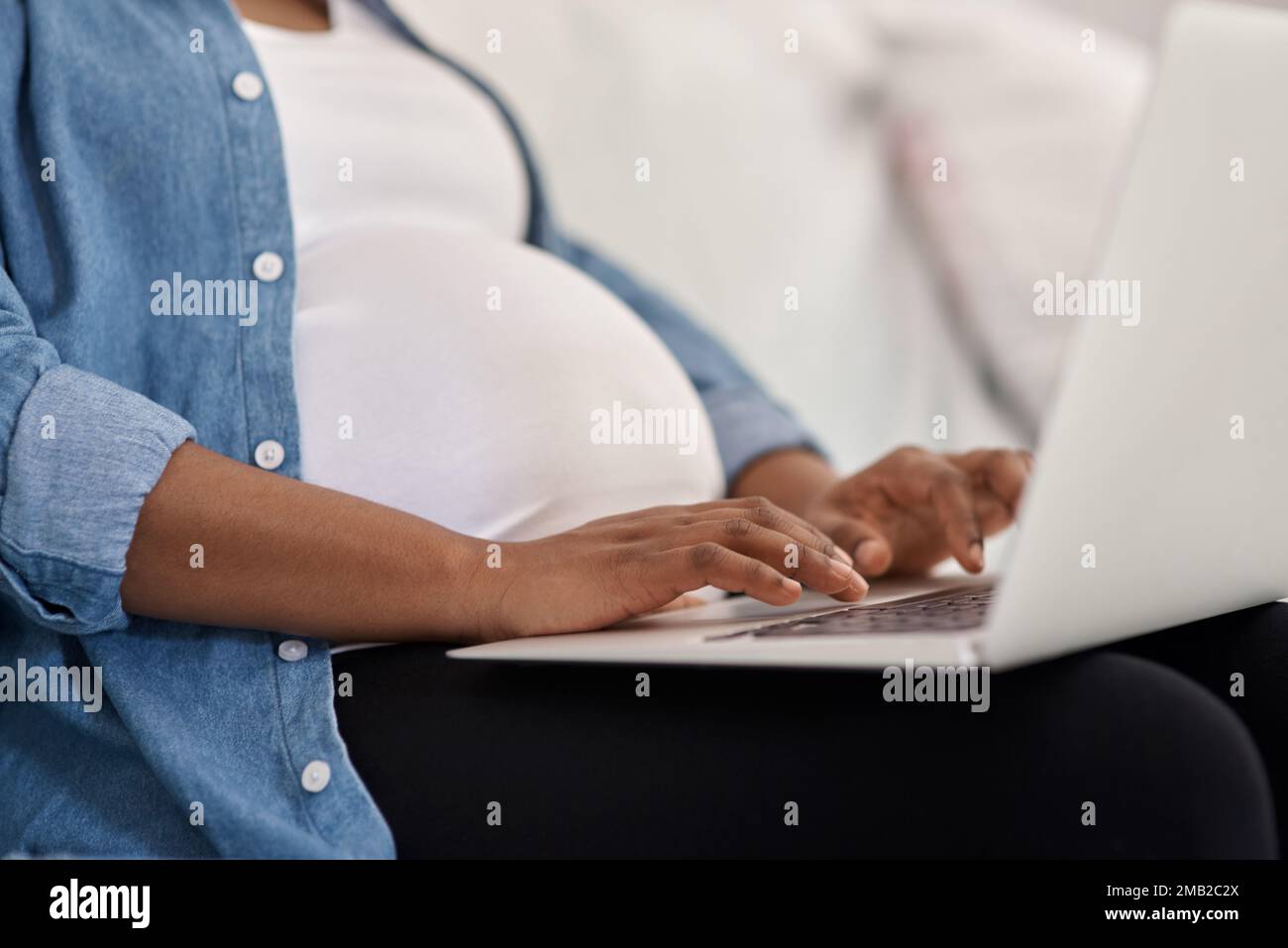 Im blogging about things to expect when youre expecting. a pregnant woman using her laptop while sitting at home. Stock Photo