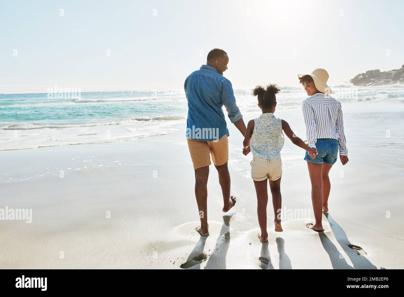 Black family, beach and walk during summer on vacation or holiday relaxing and enjoying peaceful scenery at the ocean. Sea, water and parents with Stock Photo