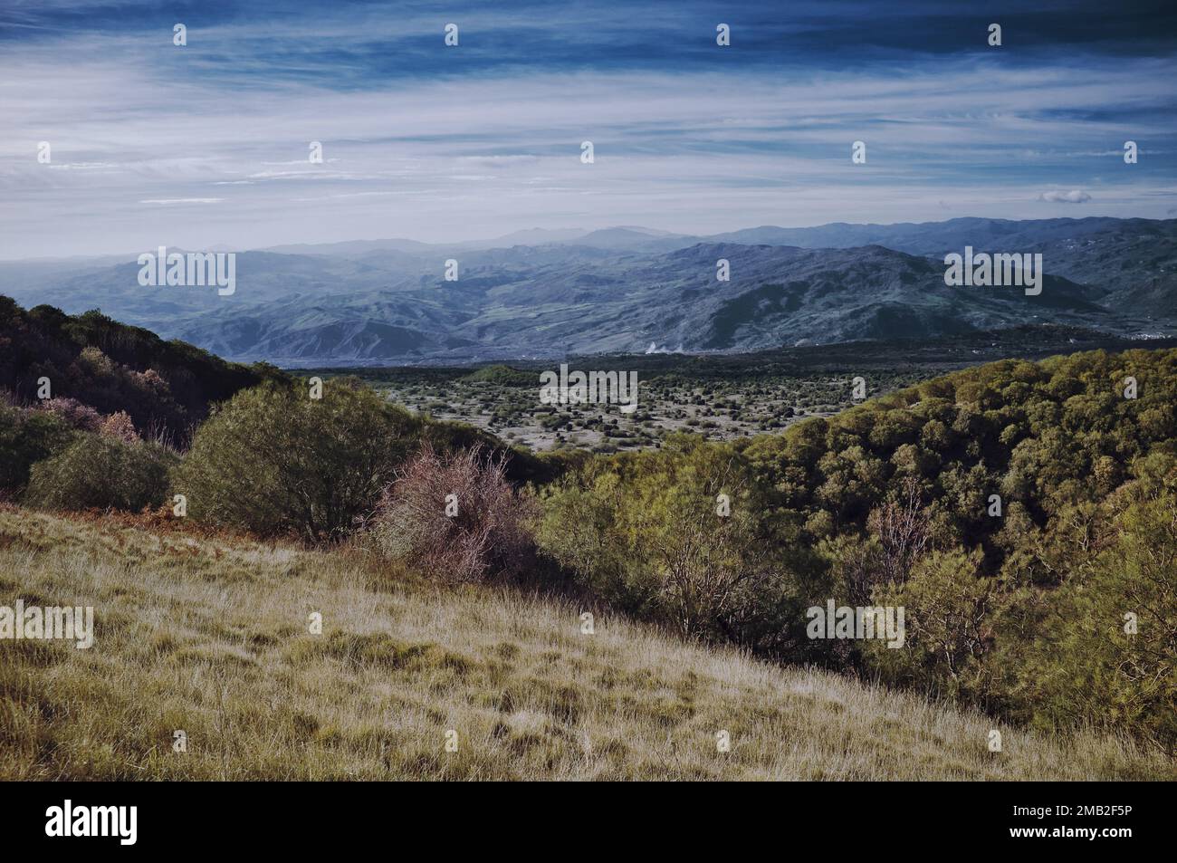 italian landscape of a open valley and distance view of a mountain range in Sicily from Etna National Park, Italy Stock Photo
