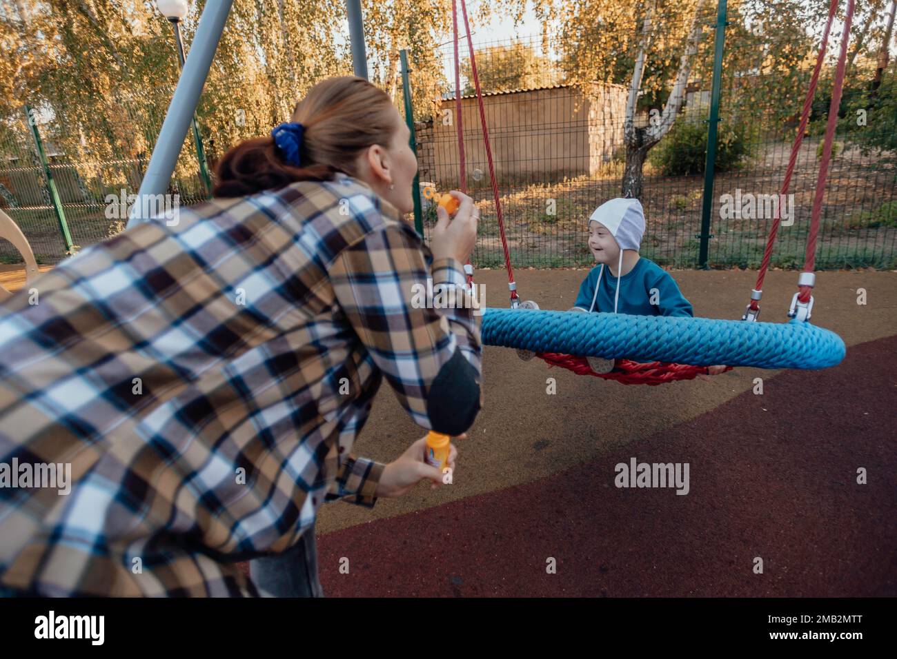 A boy, person with down syndrome walks in the park with his mother