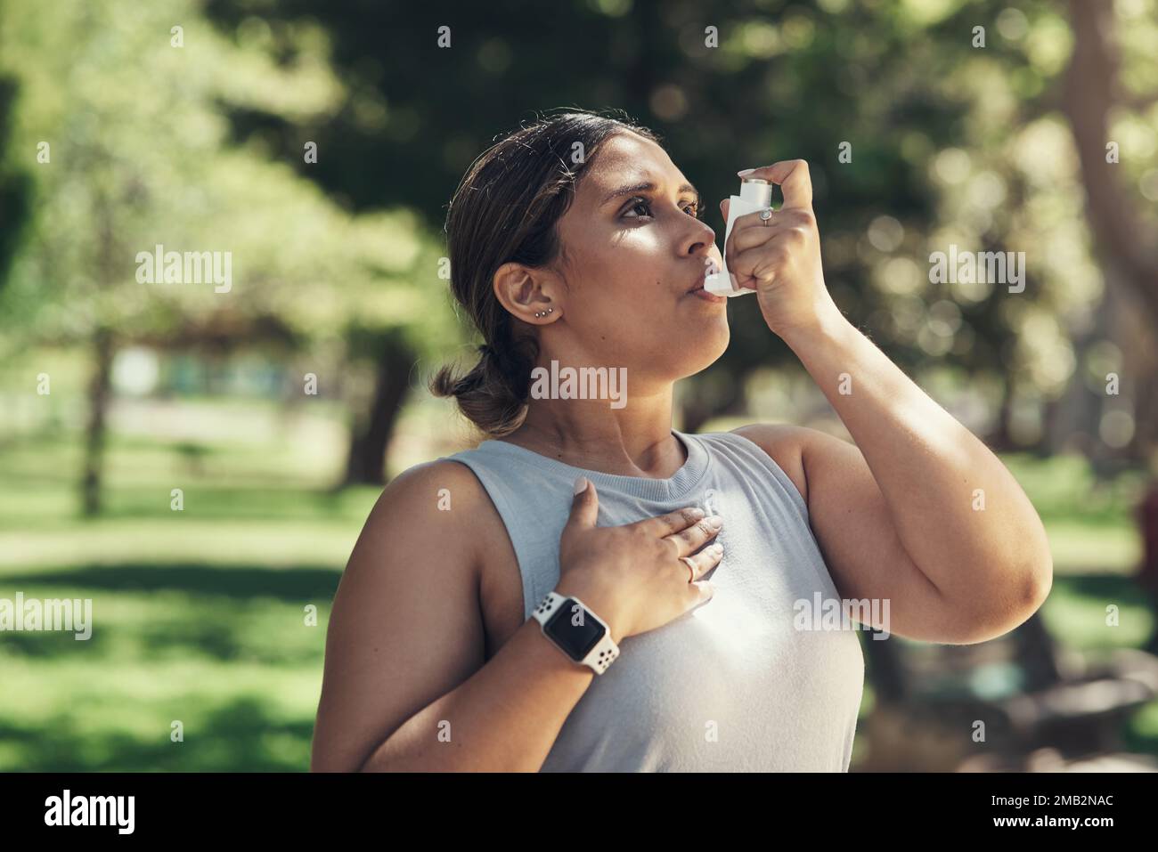 Regular exercise has really helped my asthma. a young woman taking a break during a workout to use her asthma pump. Stock Photo