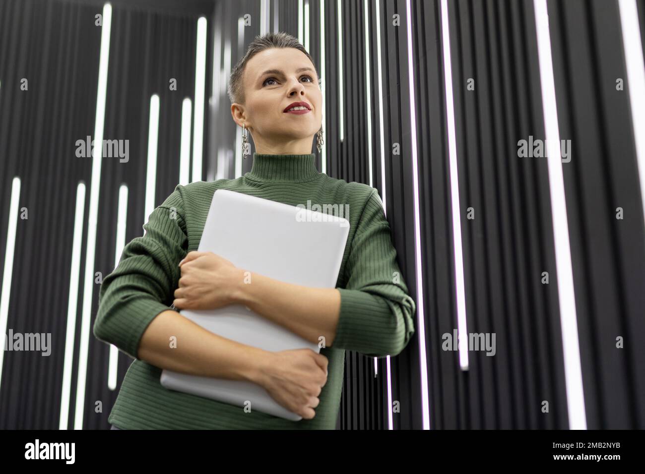 a mature woman programmer with a short haircut stands with a laptop in ...