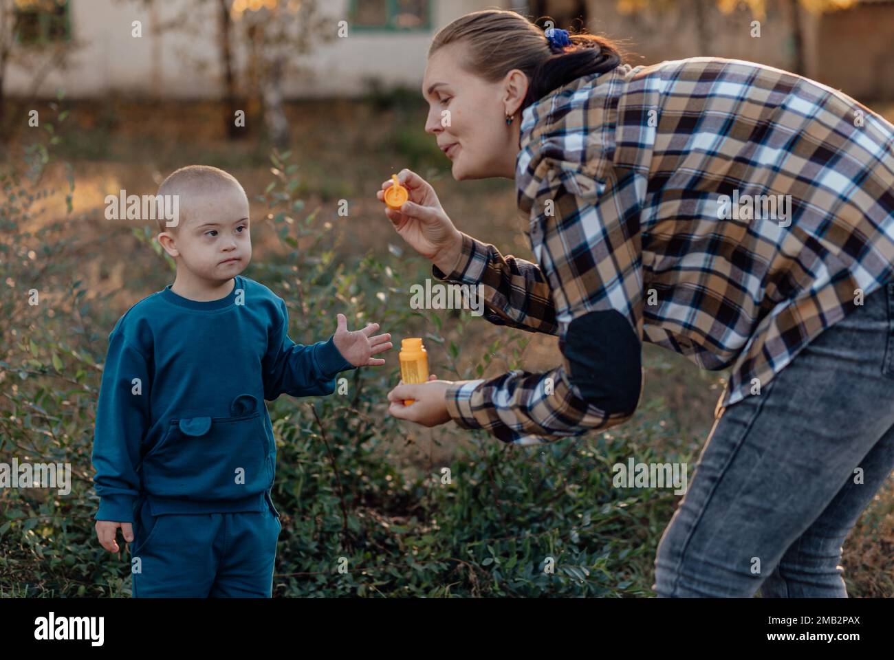 A boy, person with down syndrome walks in the park with his mother