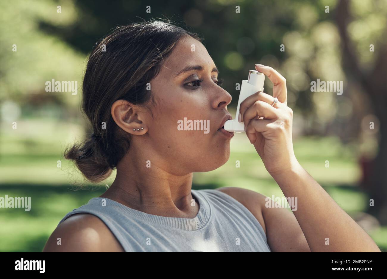 I always need to have my pump on me. a young woman taking a break during a workout to use her asthma pump. Stock Photo