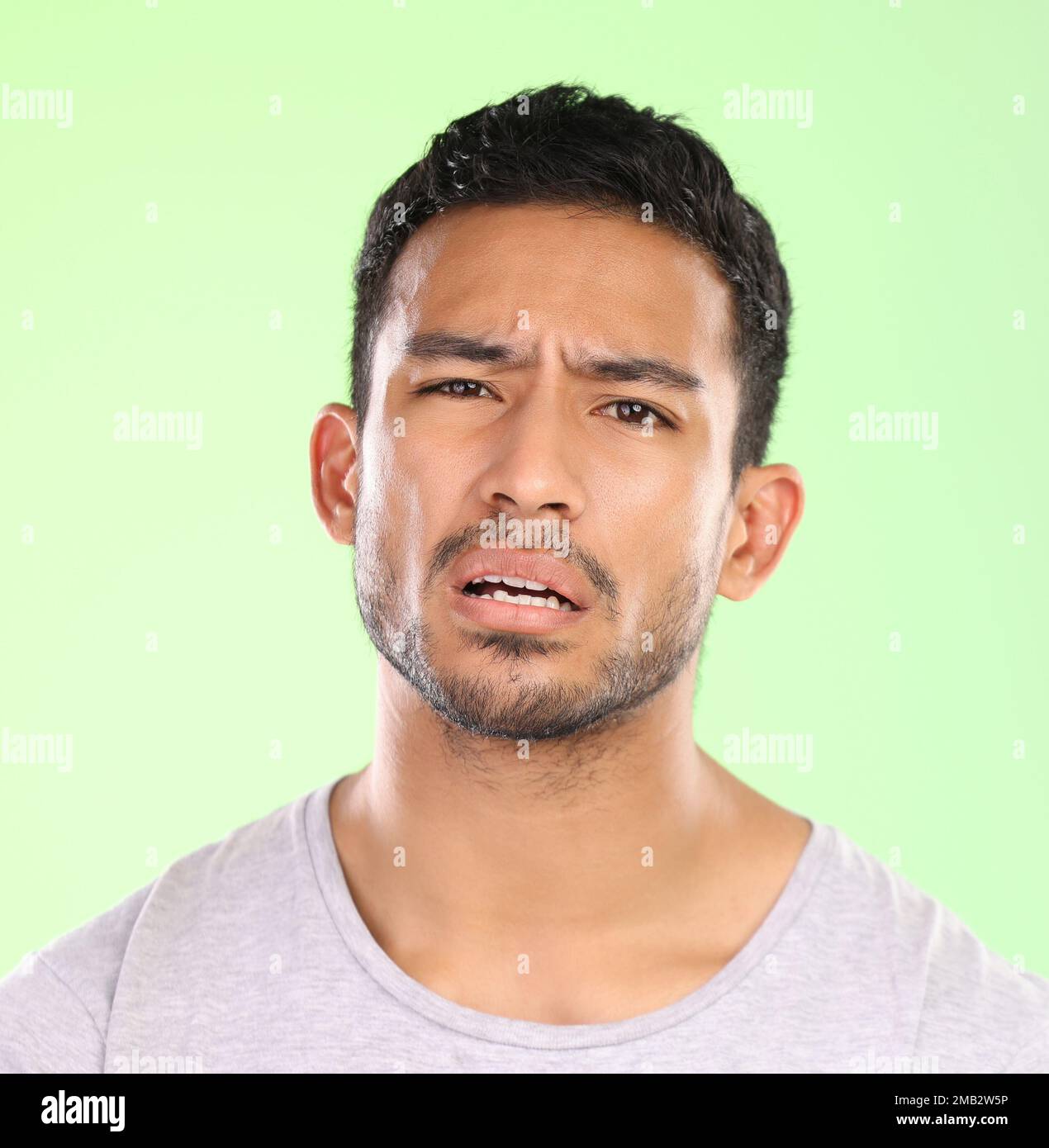 Im at a loss for words. Cropped portrait of a handsome young man making a face against a green background in studio. Stock Photo
