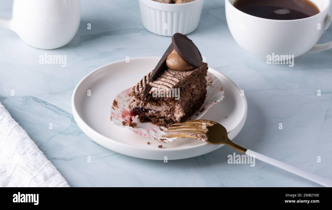 Delicious chocolate cake on plate and coffee on light table. Stock Photo