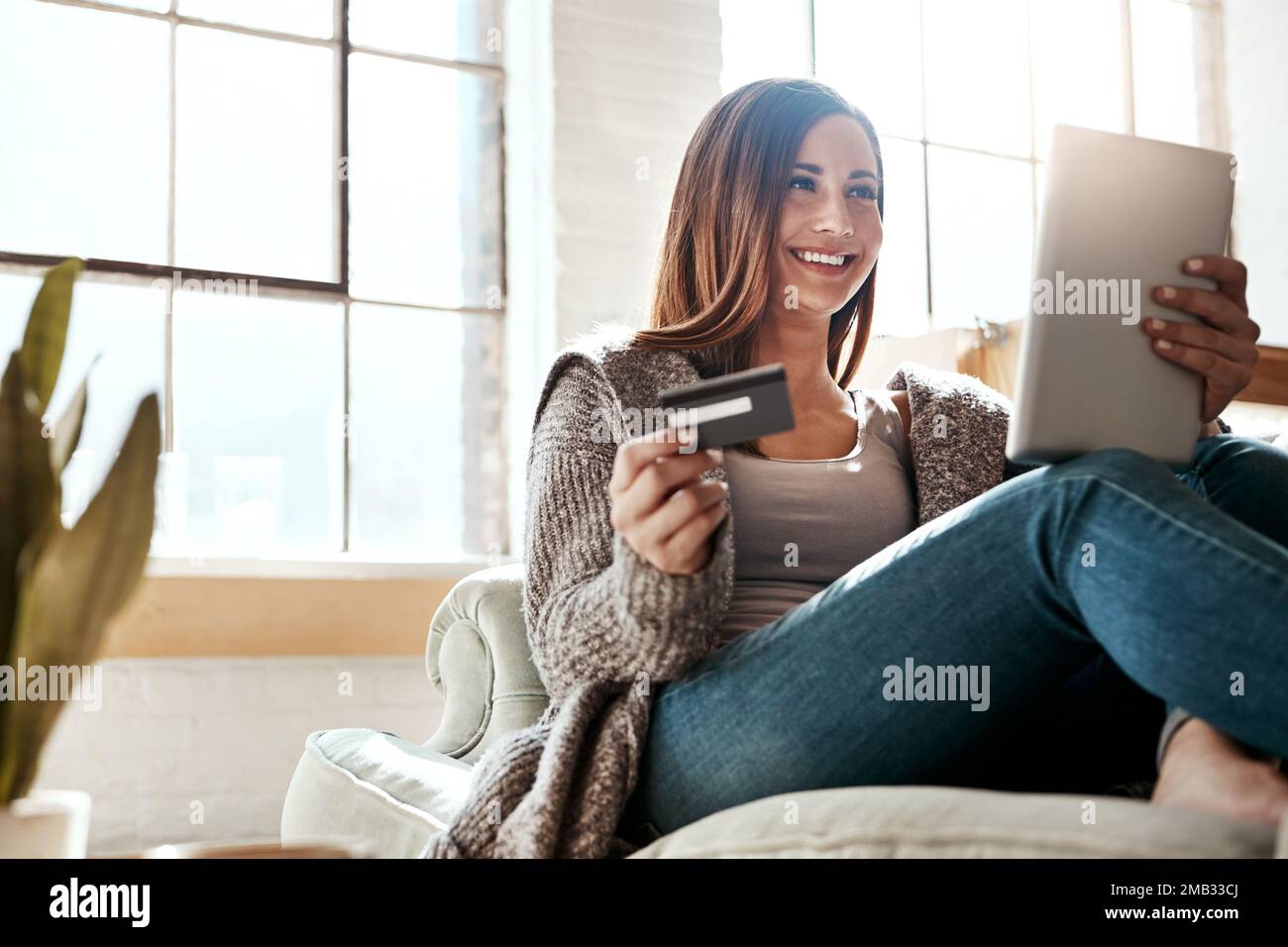 Online shopping, credit card and woman with digital tablet on a sofa, relax and smile while checking booking online. Ecommerce, girl and card for Stock Photo