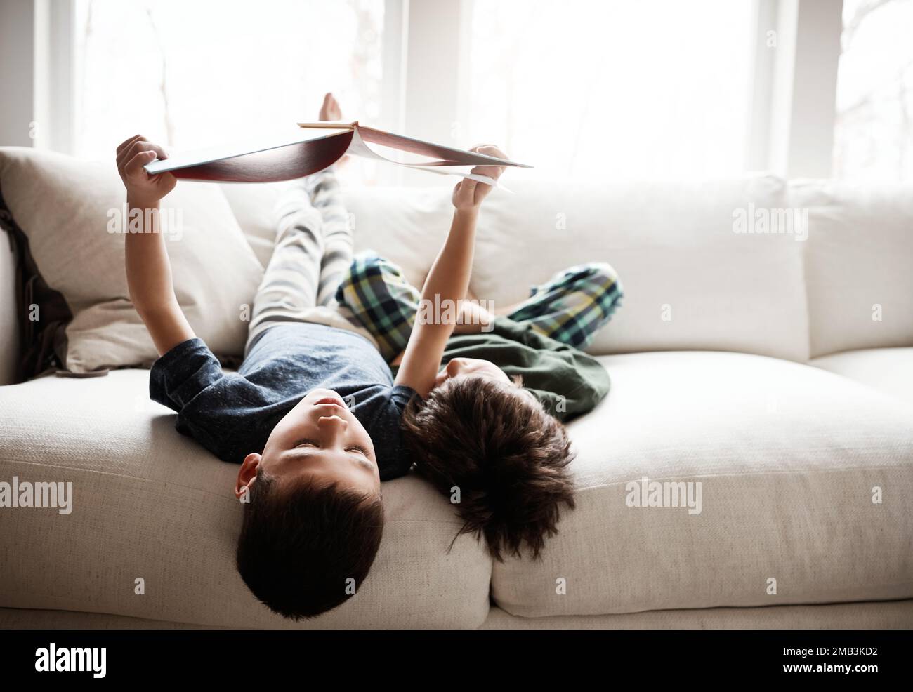 Upside down, comfortable and children reading books on sofa for knowledge, information and