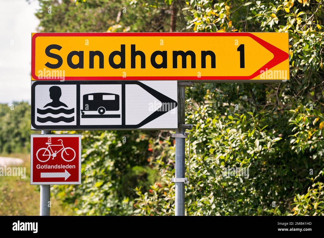 Direction sign to Sandhamn, signs bathing place by the sea and camping site, with pictogram swimmer and caravan, red traffic sign with pictogram Stock Photo