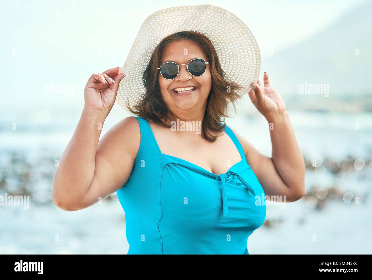 Swimsuits were made to be worn no matter your age. an attractive mature woman standing alone during a day out on the beach. Stock Photo