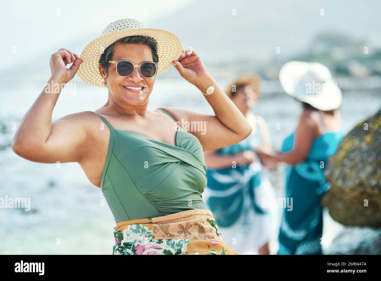 Staying young at heart is how you maintain your youth. an attractive mature woman standing and posing during a day out on the beach with friends. Stock Photo