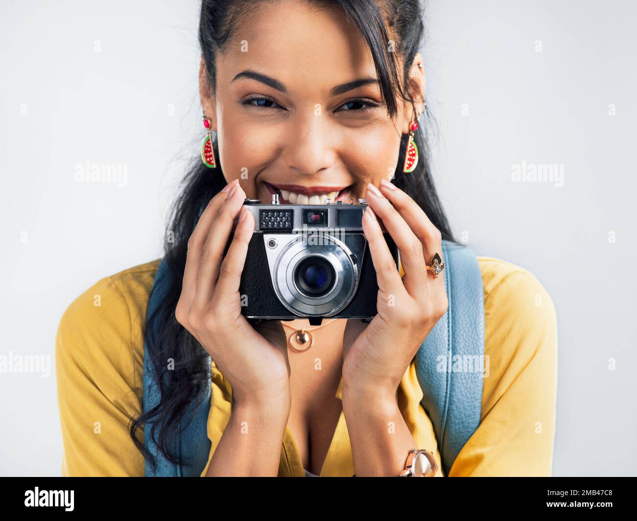 Photographs are a return ticket to every place youve been. Studio shot of a beautiful young woman holding a camera while standing against a white Stock Photo