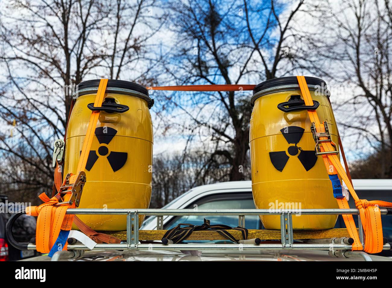 Two yellow metal barrels with signs for radioactivity on roof rack, fastened with tension belts, nuclear waste transport, radioactive waste Stock Photo