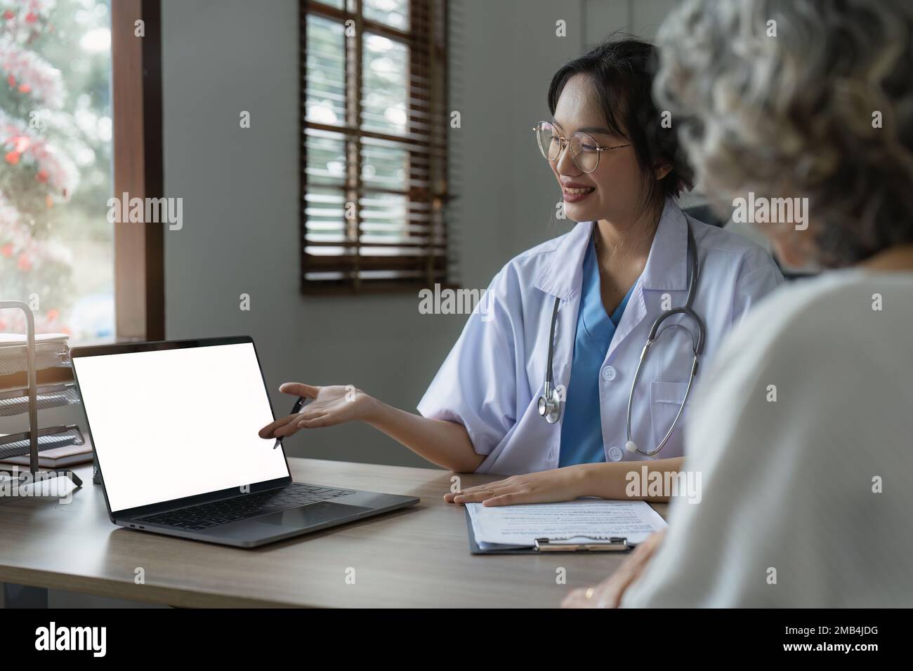 Doctor talking with elderly asian woman. Female primary care physician having conversation with older woman. Elderly Healthcare Stock Photo