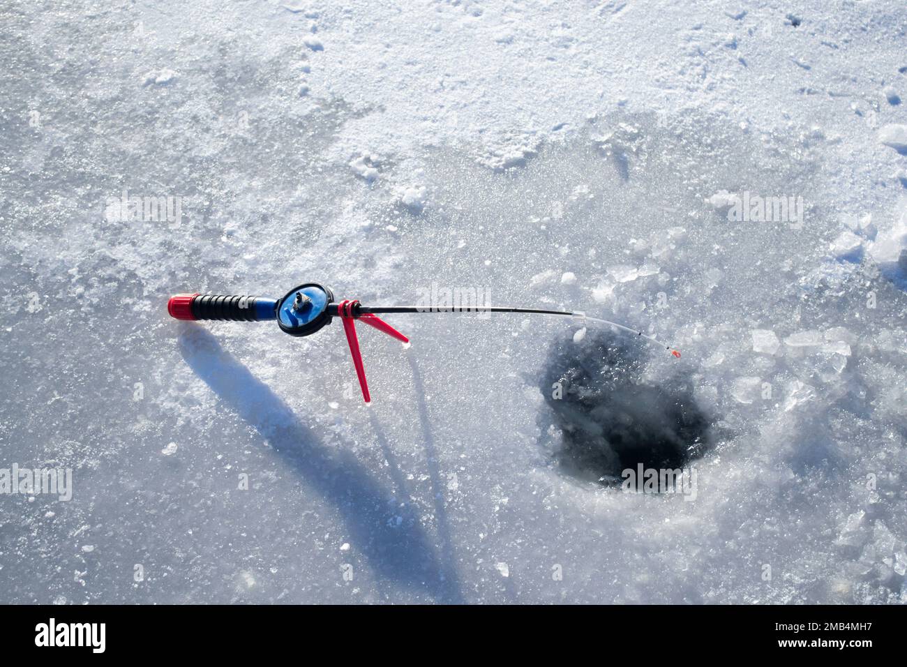 Winter ice fishing. Ice fishing in the winter. Small fishing rod stands  near a hole in the ice of a river on a sunny day. Winter activity Stock  Photo - Alamy