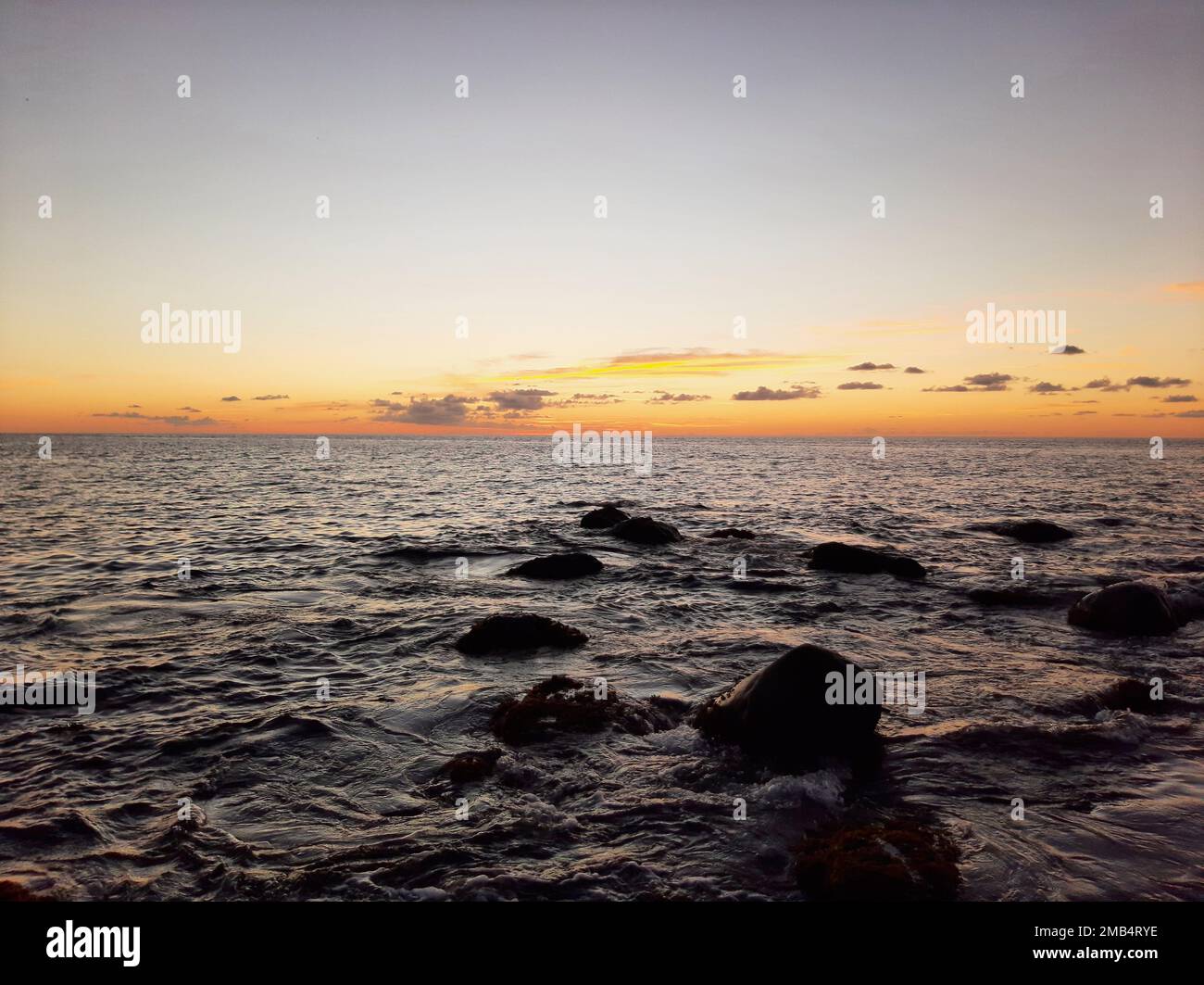 An image of a sunset in yellow sky from the wavy sea Stock Photo - Alamy