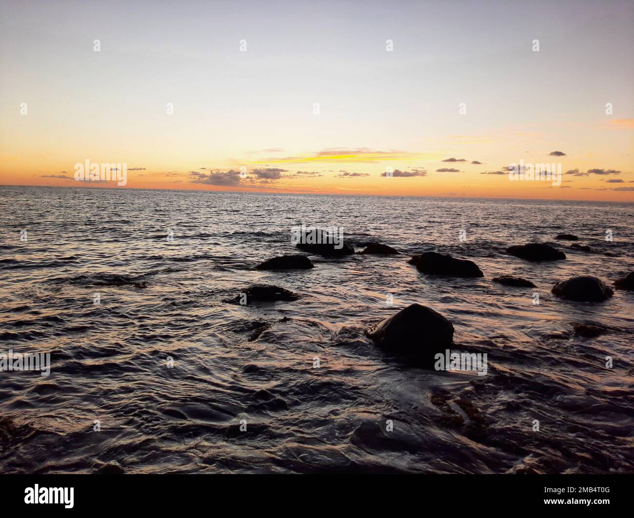 An image of a sunset in yellow sky from the wavy sea Stock Photo - Alamy