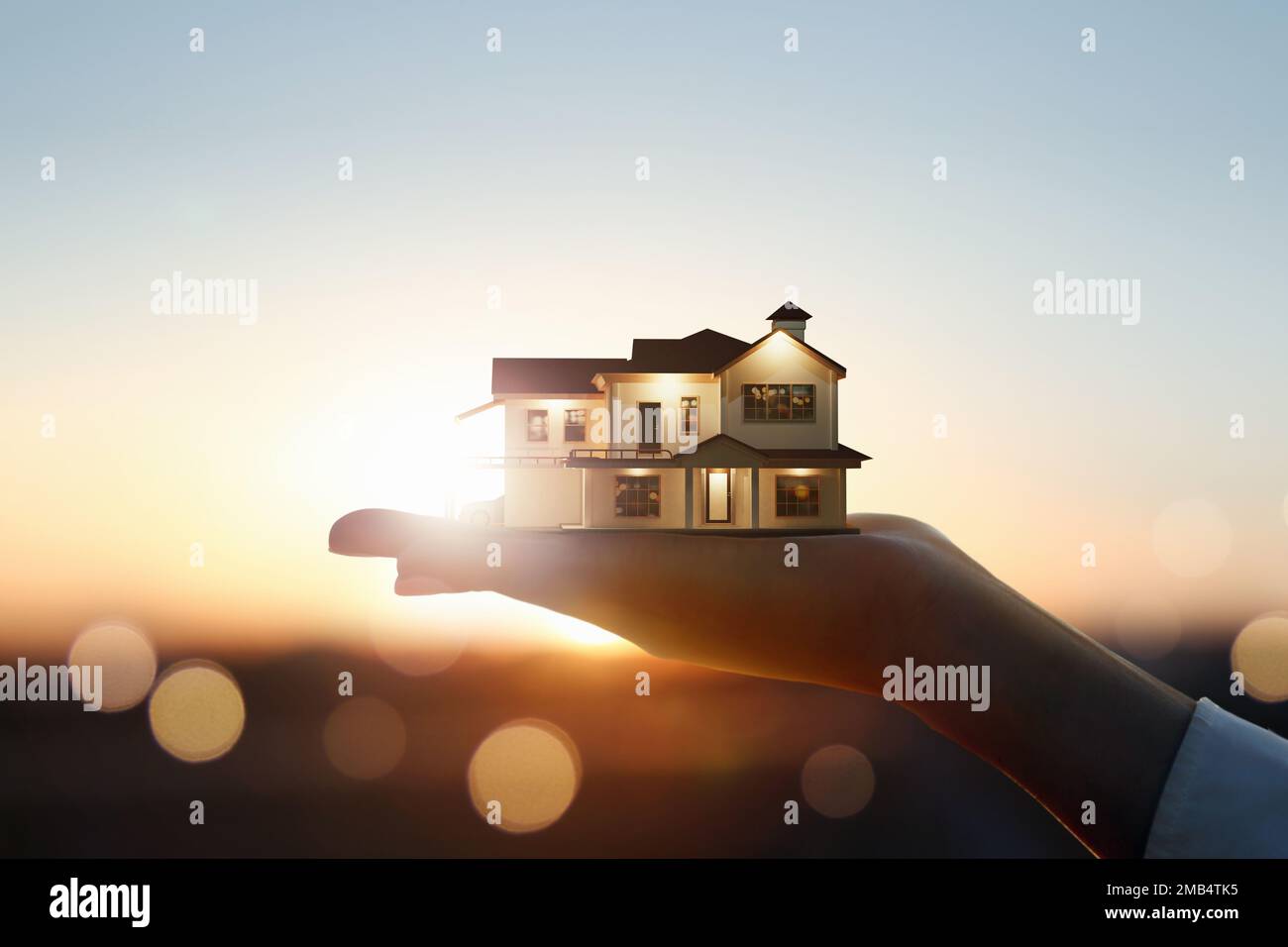 My precious home on the hands of a happy family and real estate investment and housing architecture and sunset background Stock Photo