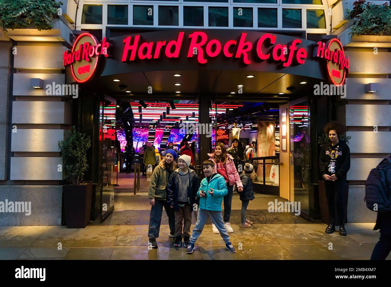 kids standing in front of the Entrance to Hard Rock Cafe with its red neon sign in Piccadilly. Stock Photo