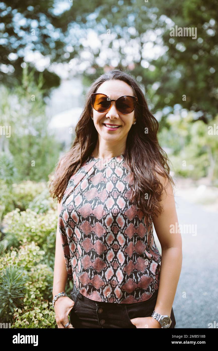 Beautiful young happy multiracial Japanese woman in jeans and shirt in summer park, smiling Stock Photo