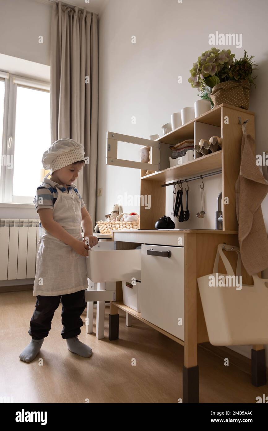 Cute little baby boy in chef hat and apron playing at childish kitchen cooking food back view Stock Photo Alamy