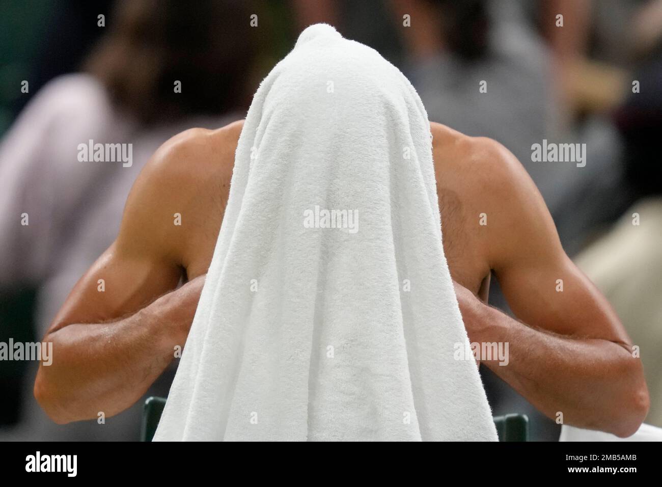 Serbias Novak Djokovic changes his shirt after the second set against Tim van Rijthoven of the Netherlands during a mens fourth round singles match on day seven of the Wimbledon tennis championships