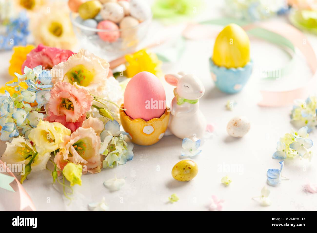 Happy Easter background with colorful eggs, candy and bunch of flowers. Table decorating for holiday. Stock Photo