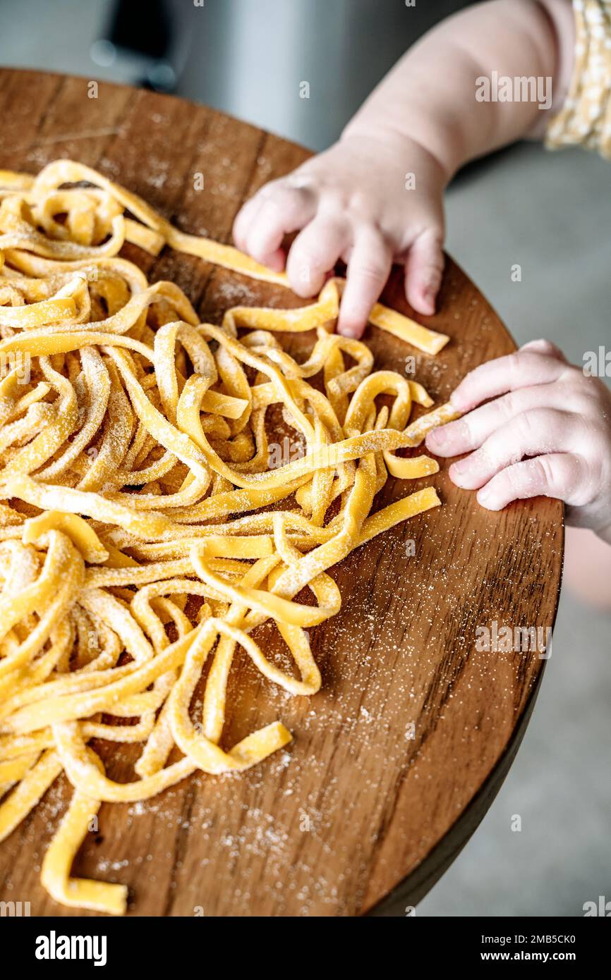 Pasta and child. Baby cooks Italian fresh pasta in the home kitchen. Selected focus. Food and kids concept. High quality photo Stock Photo