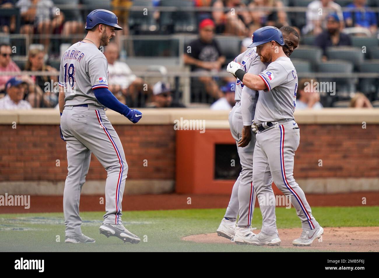 Texas Rangers' Kole Calhoun, right, celebrates with Texas Rangers' Adolis  Garcia, center, and Mitch Garver (18) after scoring a three run home run  off New York Mets starting pitcher Trevor Williams in