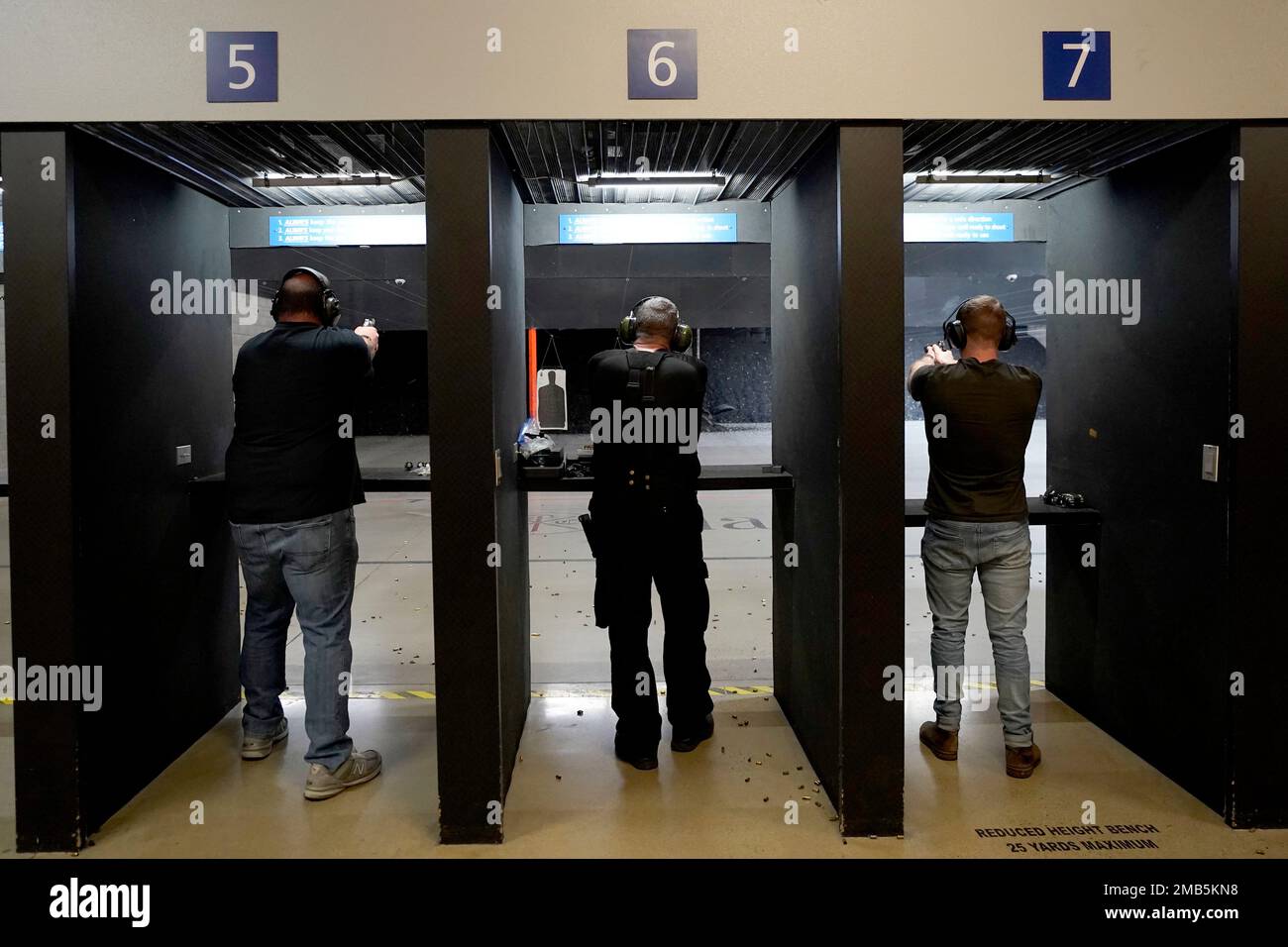 Gun owners fire their pistols at an indoor shooting range during a