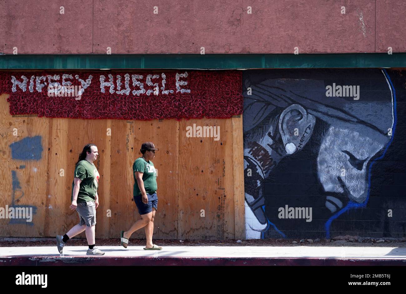 Pedestrians walk past a mural of the late rapper Nipsey Hussle