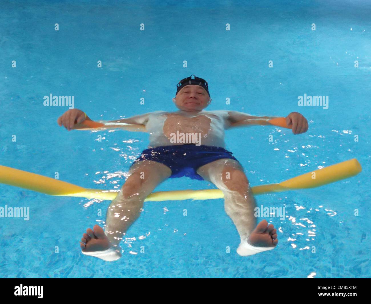 smiling man lies on the water in the pool on swimming noodles closeup