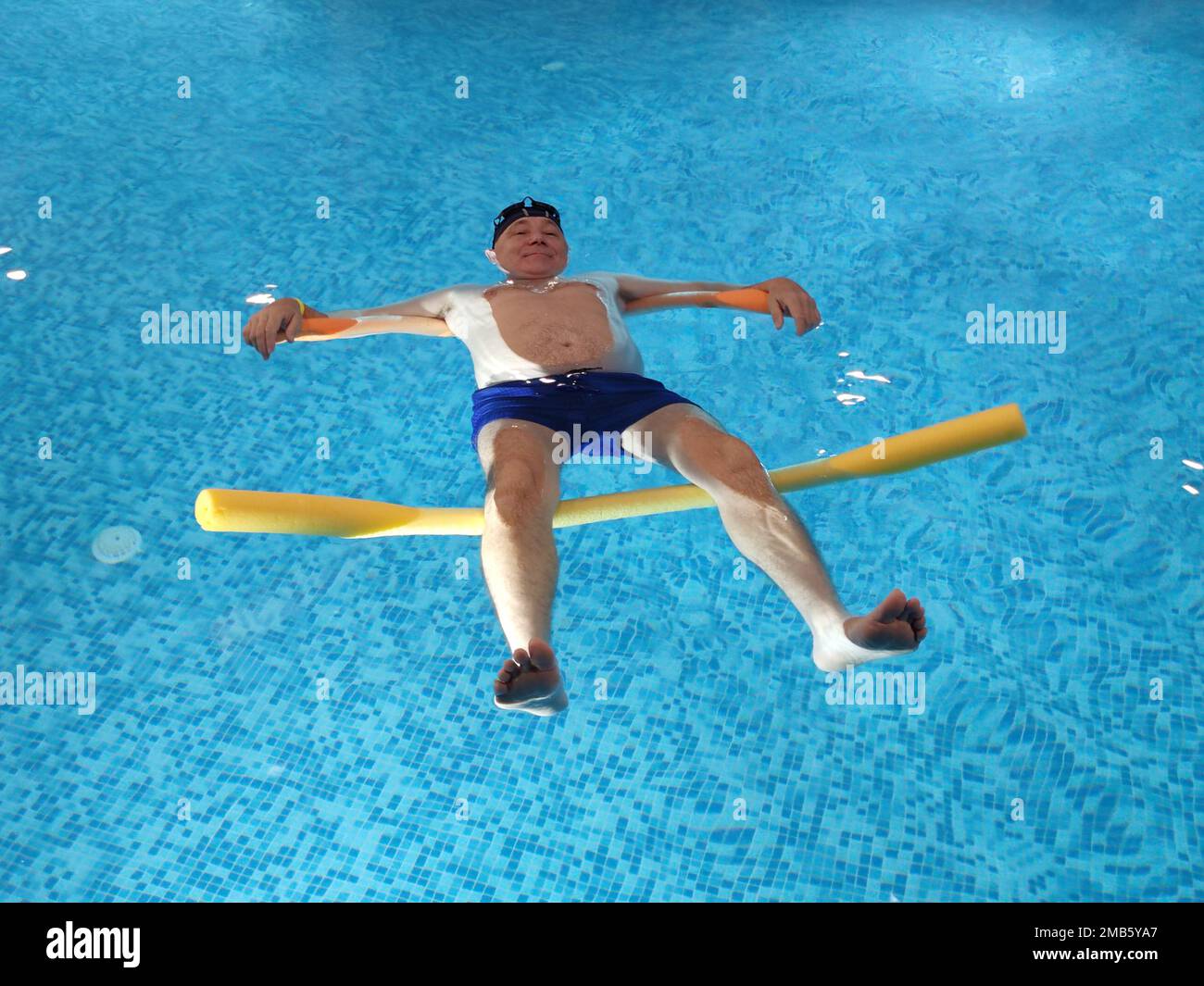 smiling man lies on the water in the pool on swimming noodles Stock