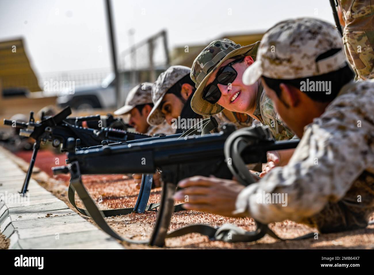 U.S. Air Force Airman 1st Class Kahrie Balding, a fireteam member assigned to the 378th Expeditionary Security Forces Squadron, simulates laying down support by fire with Royal Saudi Land Force Soldiers, Al-Kharj, Kingdom of Saudi Arabia, June 12, 2022. Eight USAF Defenders were invited by the U.S. Army to attend Task Force Hurricane’s Platoon Immersion 3 alongside the RSLF. The immersion gave the 378th ESFS members a chance to develop as multi-capable Airmen by learning both Joint Force infantry tactics and Partner Nation infantry tactics not commonly taught or practiced by the USAF. Stock Photo