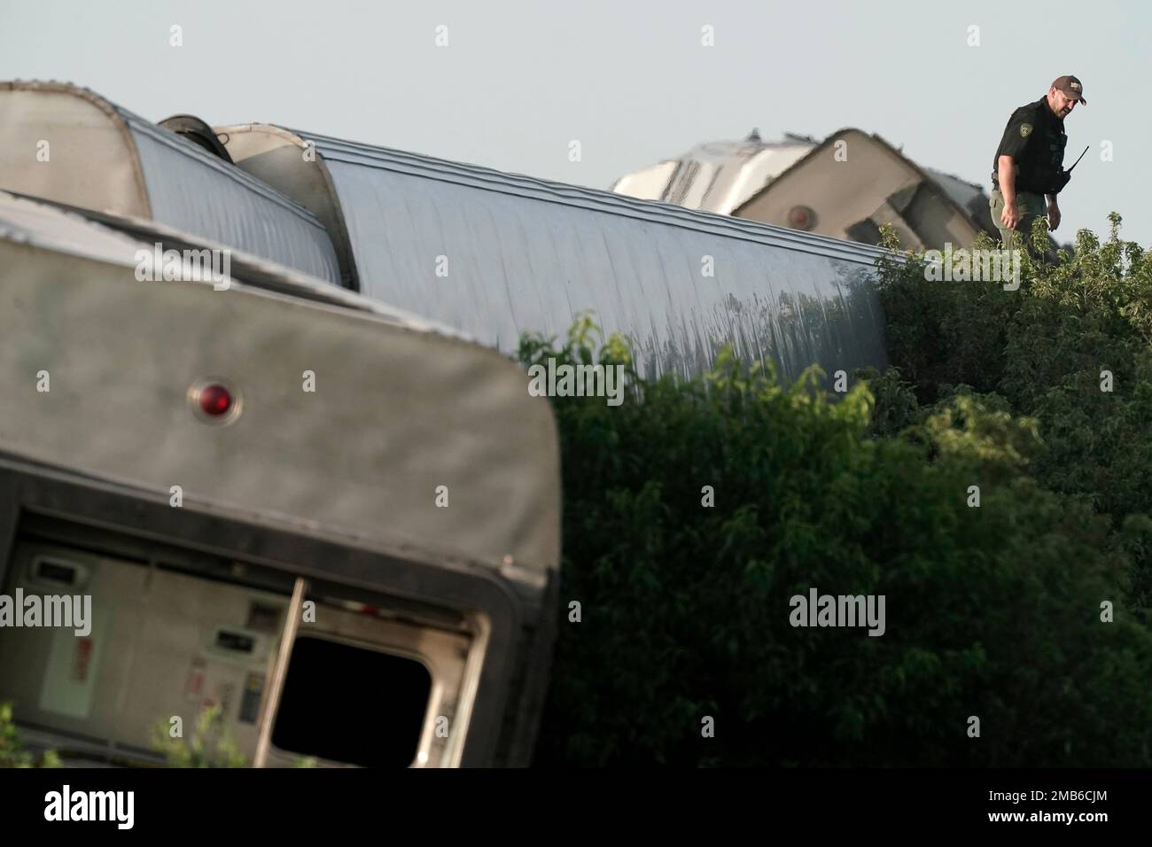 A law enforcement officer inspects the scene of an Amtrak train which