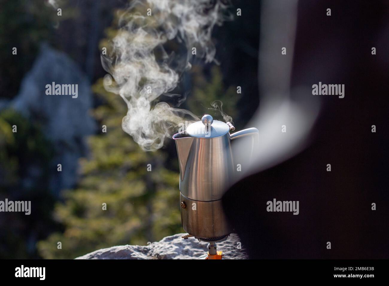 A closeup shot of steam coming out of a teapot that's boiling at a campsite Stock Photo