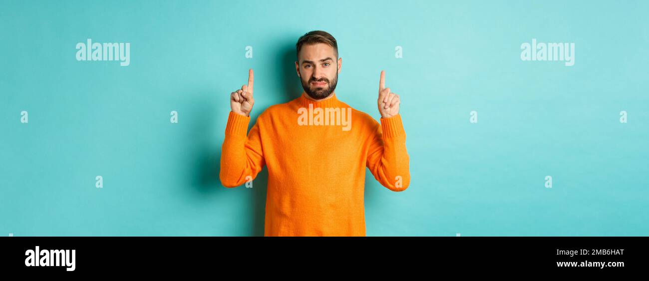 Skeptical and reluctant man looking displeased, pointing fingers up