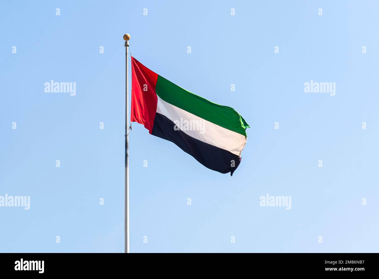 UAE flag waving in the blue bright sky, national symbol of UAE Stock